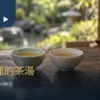 青瓷茶杯與白瓷杯並排盛茶，旁有陶壺與乾茶