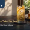 Golden oolong tea mocktail with ice and citrus peel beside plain tea in warm window light