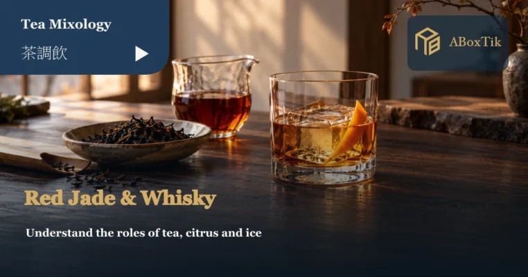 Black tea whisky with orange peel and ice beside brewed tea and dry black tea leaves