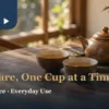 Glazed brown ceramic teapot and two cups on a warm window-side wooden table