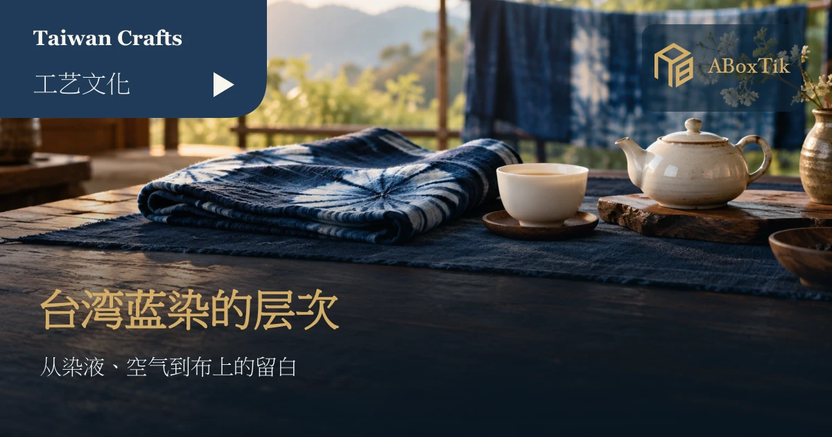 深浅蓝染布料铺在木桌上，旁有白瓷茶杯与茶壶，後方挂着蓝染布