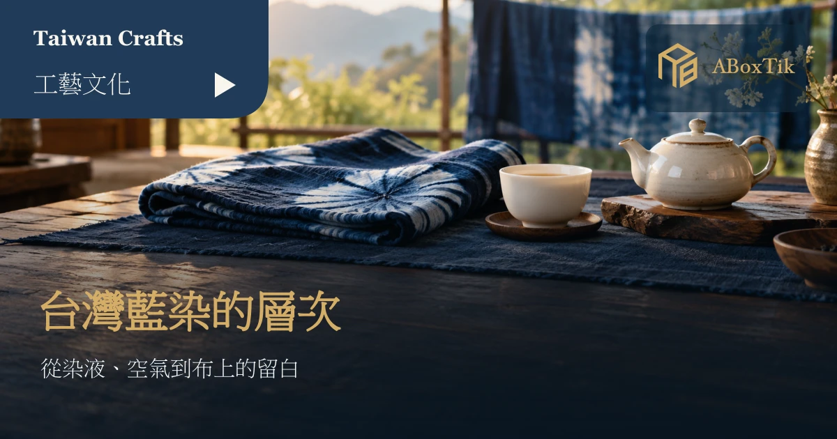深淺藍染布料鋪在木桌上，旁有白瓷茶杯與茶壺，後方掛著藍染布