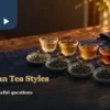 Five cups of different tea colours beside small dry-leaf dishes